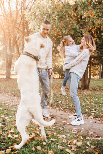 Happy family is having fun with dog labrador outdoors. © zadorozhna