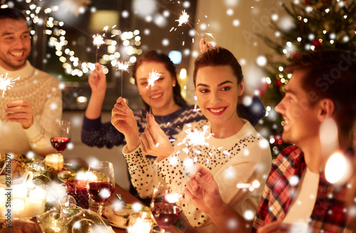 winter holidays and people concept - happy friends with sparklers celebrating christmas at home feast over snow