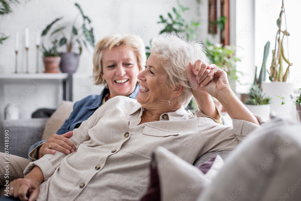 Mature lesbian couple at home on sofa фотография Stock | Adobe Stock