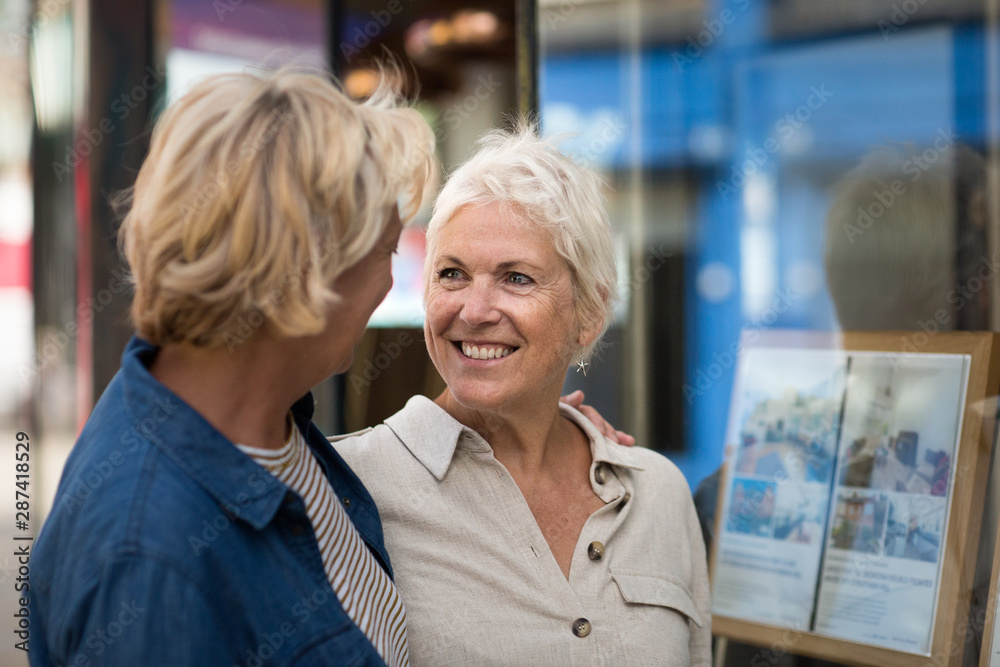 Mature lesbian couple looking at real estate agency window Stock Photo |  Adobe Stock