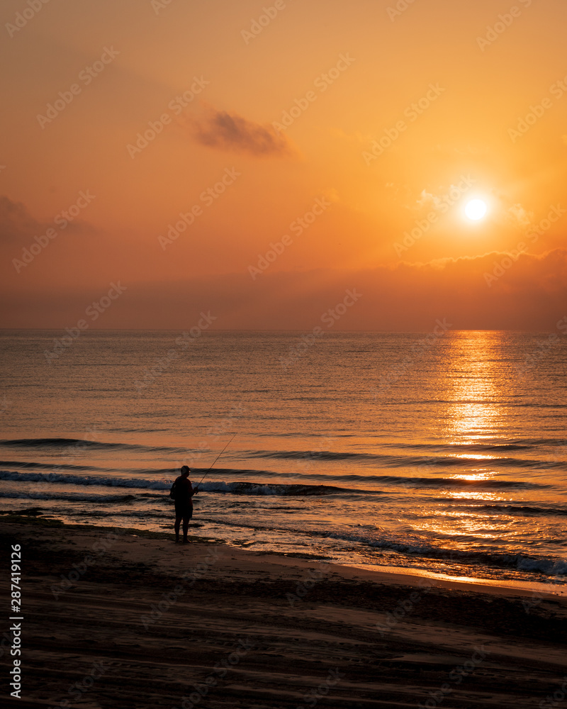 Silhouette of fisherman during sunrise