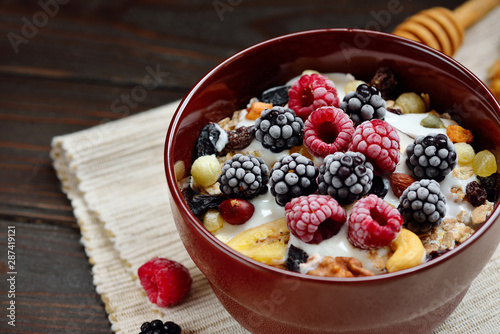Granola with yougurt, nuts, fresh berries on wooden brown background