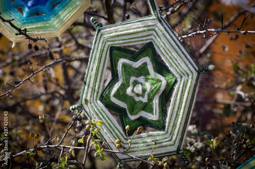 Tibetan mandala knitting with thread on the branches of a green tree. photo