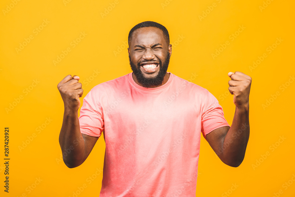 Cheerful handsome African guy making yes gesture while excited about winning. Ecstatic young fan rooting and expressing support. Success concept. Cheerful handsome African guy making yes gesture while excited about winning. Ecstatic young fan rooting and expressing support. Success concept.