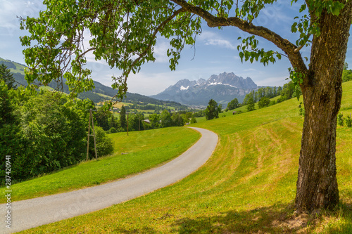 View of country lane and Ellmauer Halt Mountain peak near St. Johann, Austrian Alps, Tyrol, Austria photo