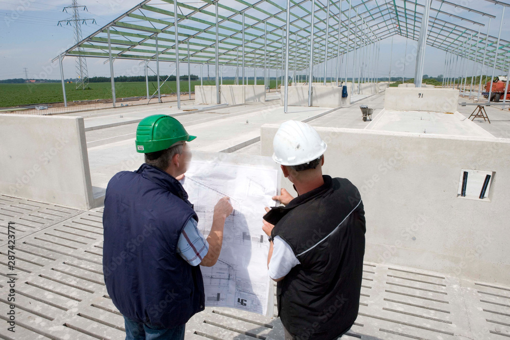 Architect and builder in discussion with building plan. Building a cattle stable. Building site. Netherlands. Construction site. Architect and builder in discussion with building plan. Building a cattle stable. Building site. Netherlands. Construction site.