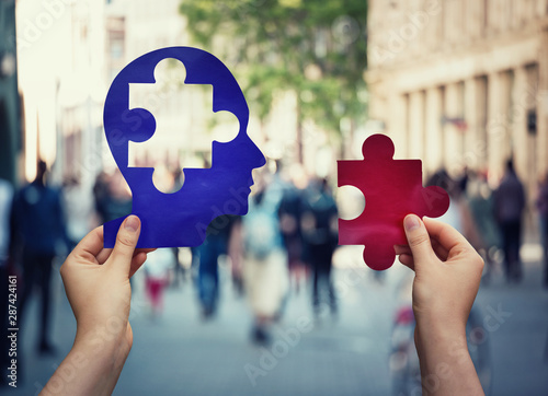 Two hands holding a paper with human head and a puzzle piece. Finding a cure to heal the disease. Mental health concept, memory loss and dementia disease. Alzheimer's losing brain and memory function. photo