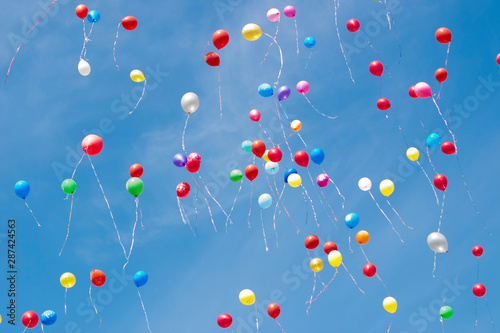 Multi-colored helium balloons fly in the sky