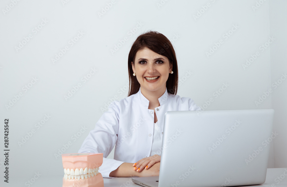 Female dentist in uniform sitting at the desk and working with dental staff in office Female dentist in uniform sitting at the desk and working with dental staff in office