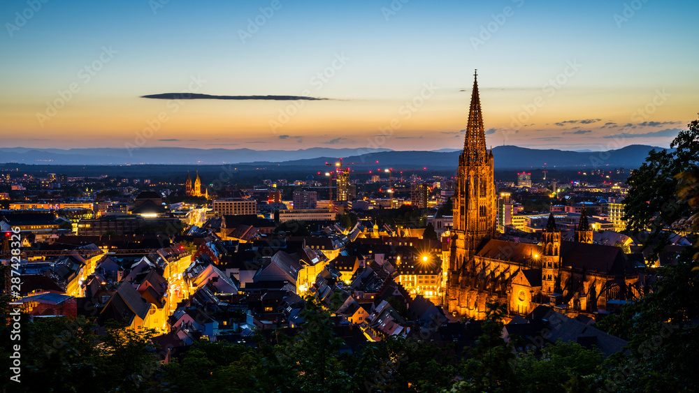 Germany, Freiburg im breisgau cityscape and minster or muenster cathedral in magical atmosphere after sunset in summer from famous square above the city
