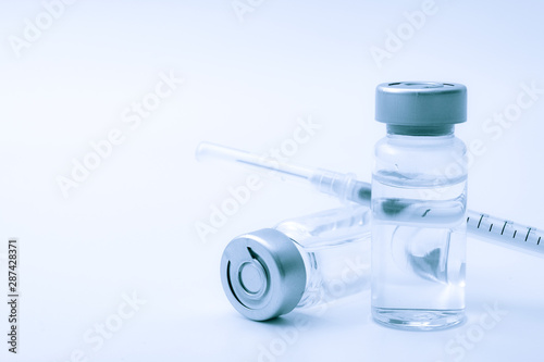 Vaccines, botulinum toxin and insulin ampules concept theme with glass vials with clear liquid next to a syringe and a hypodermic needle isolated on white background