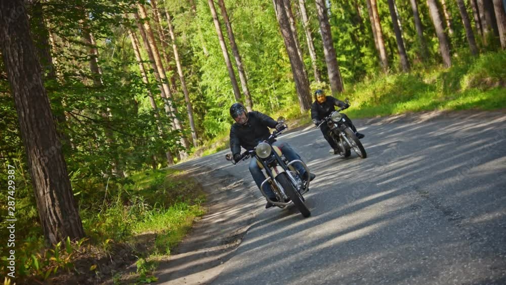 Two brutal men motorcyclists in helmet riding a motorbike in the forest - a camera following the moves of bikers Two brutal men motorcyclists in helmet riding a motorbike in the forest - a camera following the moves of bikers