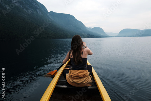 Young woman canoeing in the lake bohinj on a summer day  background alps mountains.