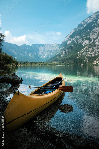 canoeing in the lake bohinj on a summer day, background alps mountains.