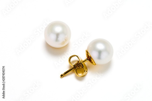 White cultured pearls on gold post make up these earring studs. Set on a white background.