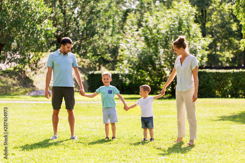 family, leisure and people concept - happy mother, father and two little sons holding hands at summer park