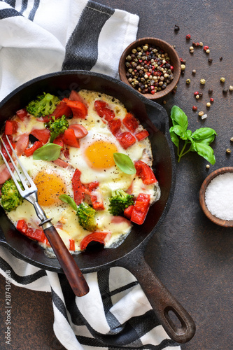 Fried eggs with tomatoes, peppers and broccoli for breakfast on the kitchen table. Good morning.