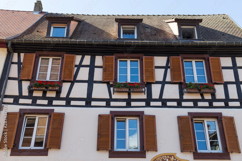Fototapeta premium Colorful wall of old half-timbered house with multiple windows and wooden shutters, close-up.