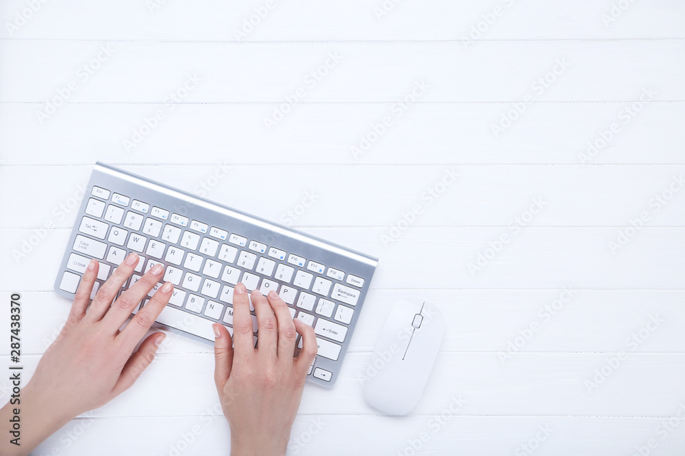 Female hands typing on computer keyboard on wooden table Female hands typing on computer keyboard on wooden table