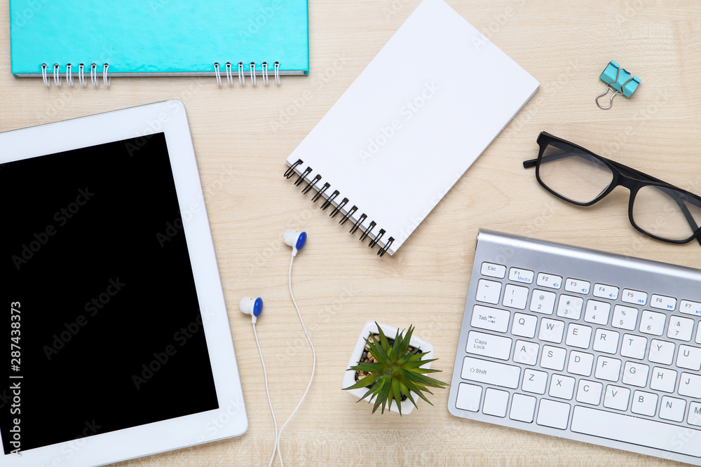 Tablet and computer keyboard with office supplies on wooden table Tablet and computer keyboard with office supplies on wooden table