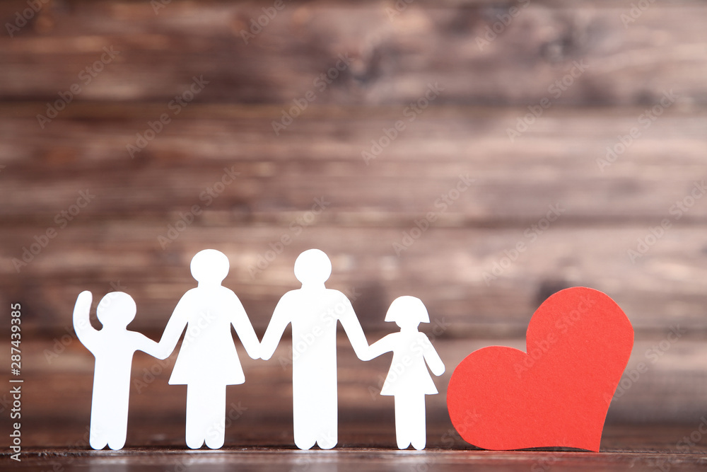 Family figures with red heart on brown wooden table - obrazy, fototapety, plakaty 