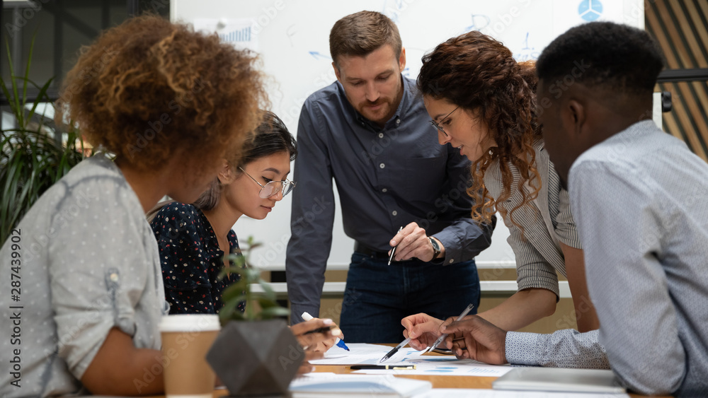 Fototapeta premium Focused multiethnic business people work together discuss paperwork at meeting