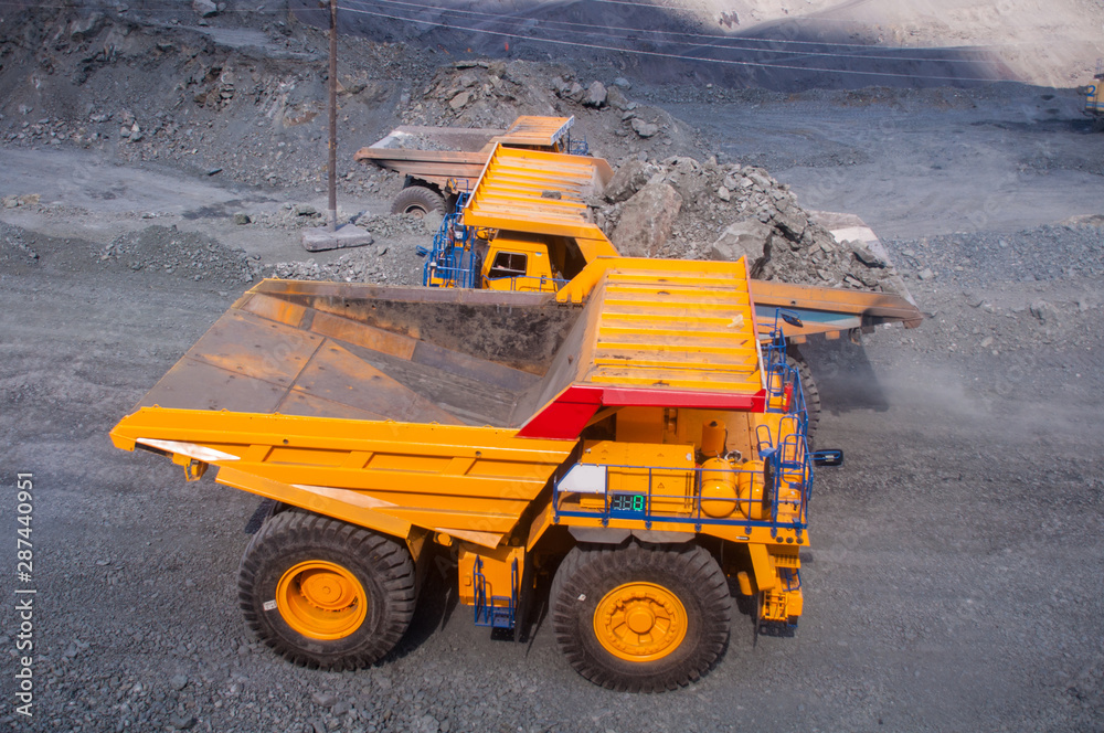 mining machinery works in a quarry. Trucks are transporting ore. excavators load ore into dump trucks.