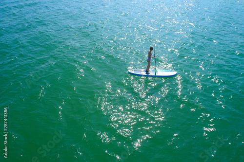 Aerial drone birds eye view of young woman exercising sup board in turquoise tropical clear waters © sarymsakov.com