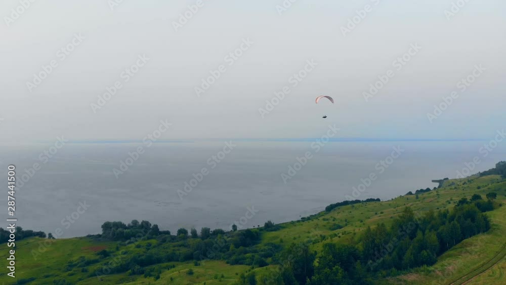 Sportsman flying with a paraglider in sky over fields. Sportsman flying with a paraglider in sky over fields.