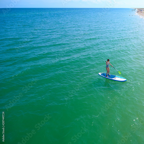 Aerial drone birds eye view of young woman exercising sup board in turquoise tropical clear waters © sarymsakov.com