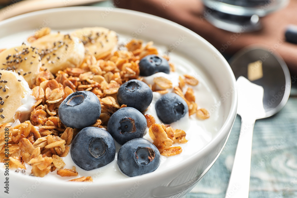 Bowl of yogurt with blueberries, banana and oatmeal on wooden table, closeup Bowl of yogurt with blueberries, banana and oatmeal on wooden table, closeup