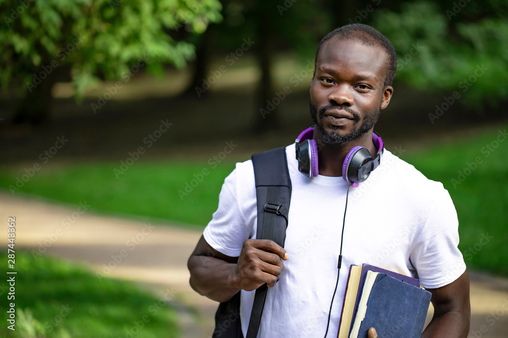 Portrait of a modest african male student on his way to classes through campus park Portrait of a modest african male student on his way to classes through campus park