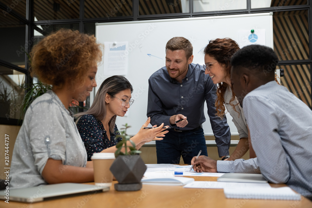 Asian employee telling idea multiethnic project team at office meeting Asian employee telling idea multiethnic project team at office meeting