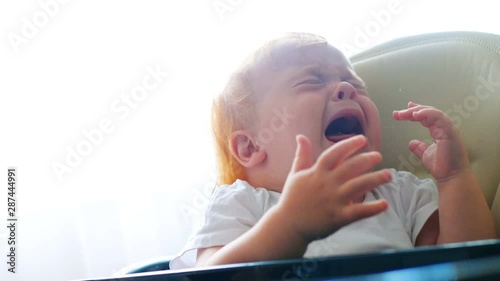Close shot of mother feeding her little baby girl with teaspoon. She don't like to eat puree, cry and scream loudly. Child refuses to eat with tears
