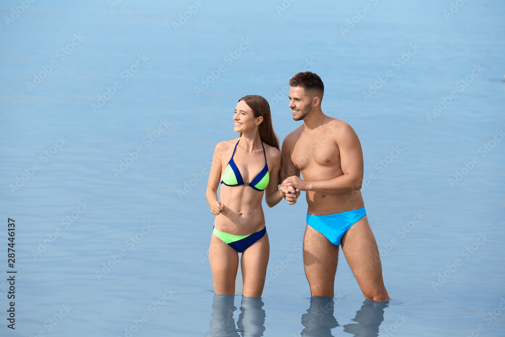 Young woman in bikini with her boyfriend in sea, space for text. Lovely couple Young woman in bikini with her boyfriend in sea, space for text. Lovely couple