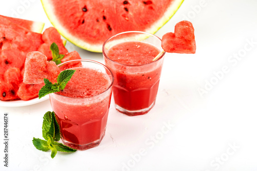 Watermelon smoothie fresh juice with mint, pieces of watermelon in the shape of hearts and slices of watermelon. Healthy drinks in glasses on a white background.
