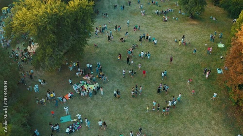 Crowd of people are walking, playing and having a picnic outdoors at summer. People having their carefree time in public park. Aerial view from above 4k