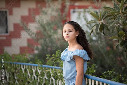 Beauty romantic girl outdoors. Teenage kid in a city street dreams and thinks, looking away from the camera.