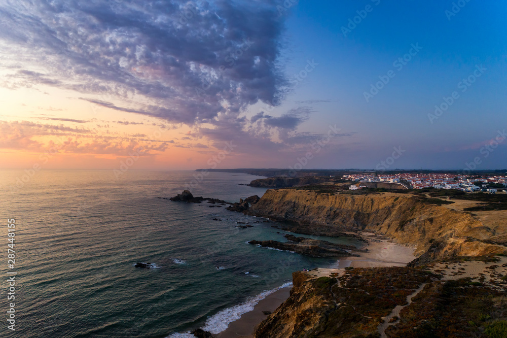 Aerial view of the Zambujeira do Mar village and beach at sunset, in Alentejo, Portugal;