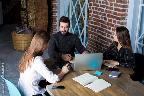 Teamwork of successful business content writers, talking about work, using laptop computer. Students learning online in university library. CEO having interview with new employees sitting in office