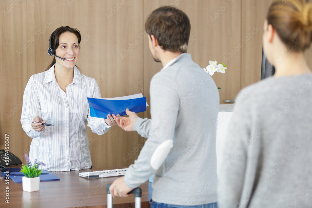 Fototapeta premium receptionist wearing headset passing file to man