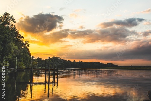 Idealized Artistic focus of a beautiful sunset over a river with a dock and lily pads in foreground with colorful cloudscape