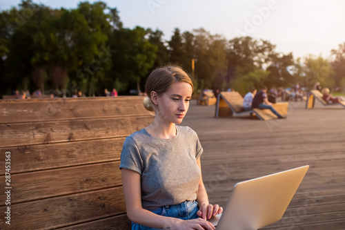 Attractive woman university student having online education via portable laptop computer while resting on a campus. Hipster girl skilled social network administrator working distance via netbook