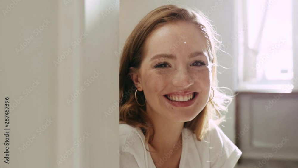 Smiling beautiful face young woman sitting look at camera at home indoors at sunlight charming attractive female girl happy modern portrait close up slow motion Smiling beautiful face young woman sitting look at camera at home indoors at sunlight charming attractive female girl happy modern portrait close up slow motion