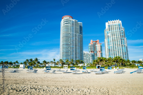 Bright scenic morning view of the Miami skyline with lounge chairs waiting for sunbathers on the shore of South Beach at South Pointe © lazyllama