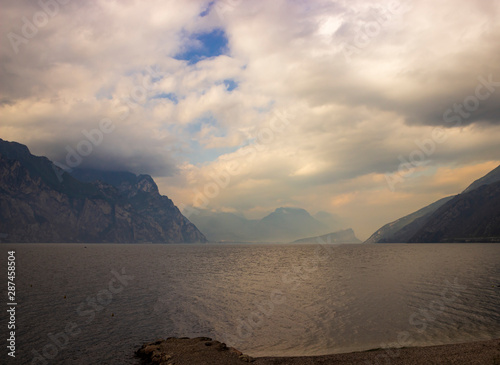 Stone shore of the lake Garda. Fog over the water on a cloudy day. Soft focus and blurred background.