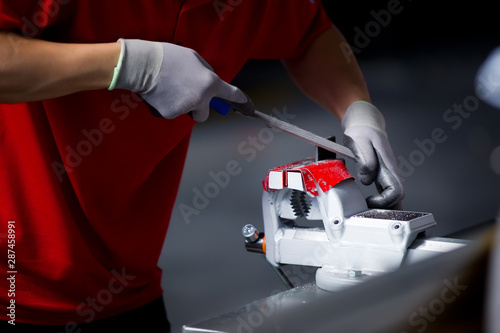Wallpaper Mural close-up of a worker in a red t-shirt processing a metal workpiece clamped in a vice Torontodigital.ca