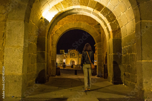 Avila, Castilla y Leon / Spain »; Fall of 2019: A young woman walking through a tunnel in the wall at night