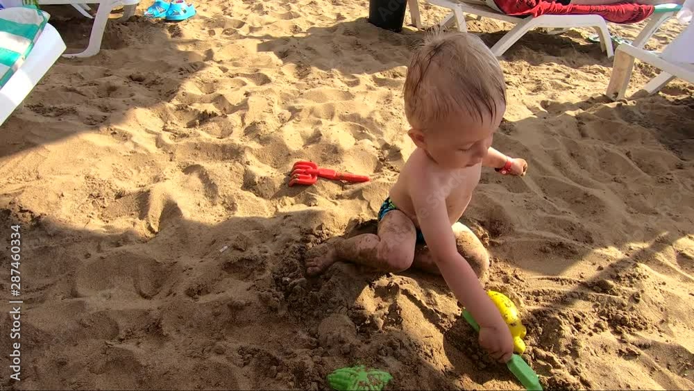 The cute little boy playing toys with sand at sea beach. Child os on vacation in summer at the beach on vacations. The cute little boy playing toys with sand at sea beach. Child os on vacation in summer at the beach on vacations.