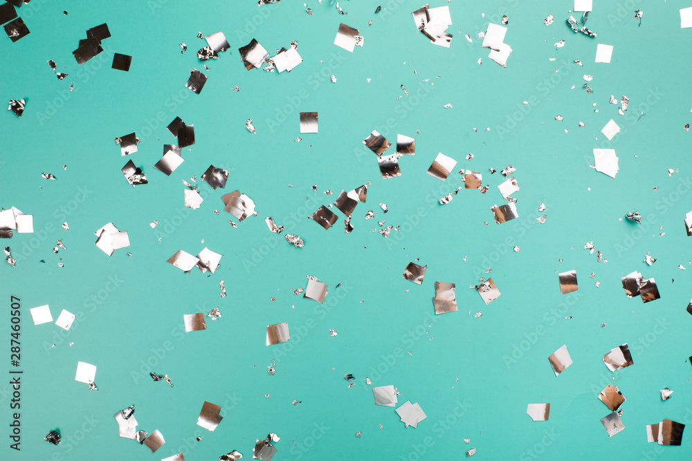 Falling silver confetti on mint backdrop. Holiday concept. Falling silver confetti on mint backdrop. Holiday concept.